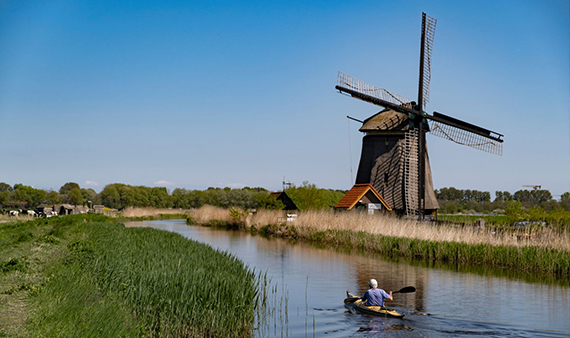 Uitzicht Weidse Polders met sloot, bootje en op een molen